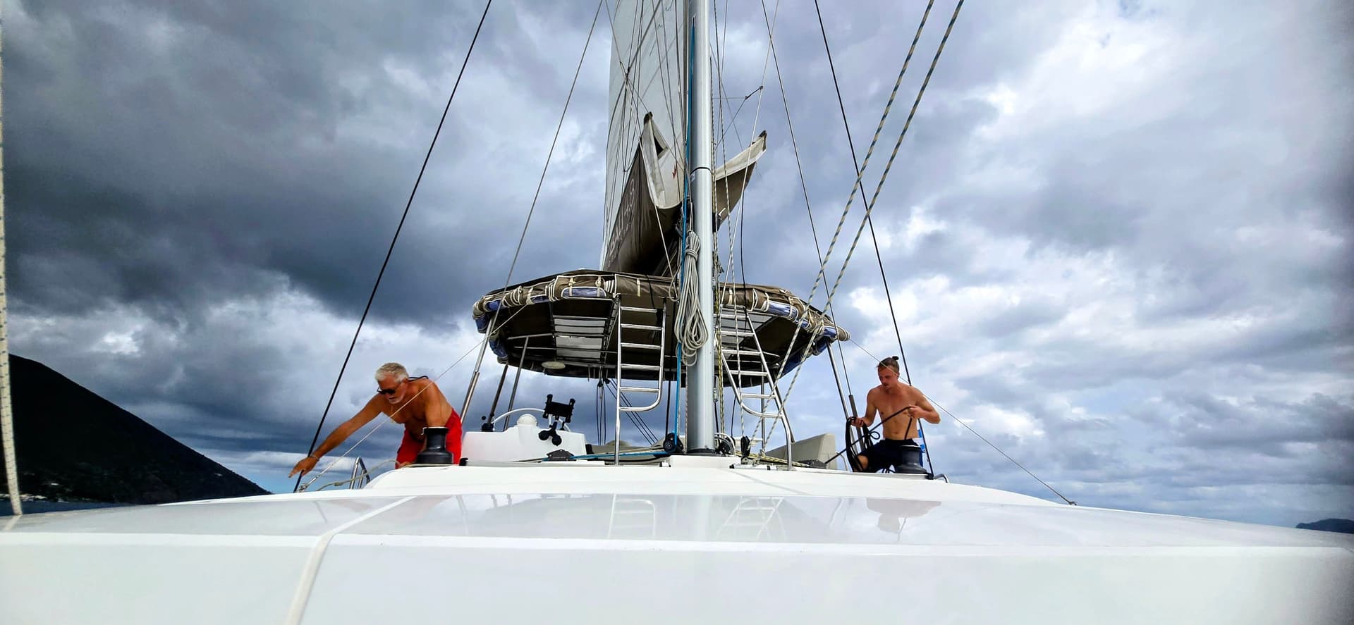 deux hommes en maillot de bain à bord d'un bateau à voile bali catamaran