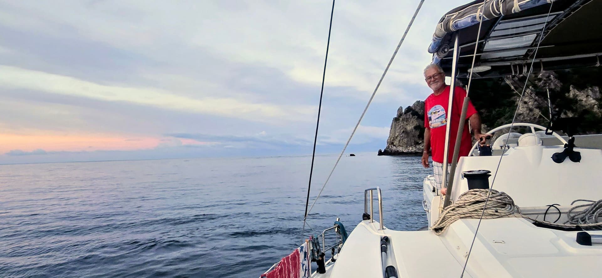 homme à la barre de son voilier bali catamaran